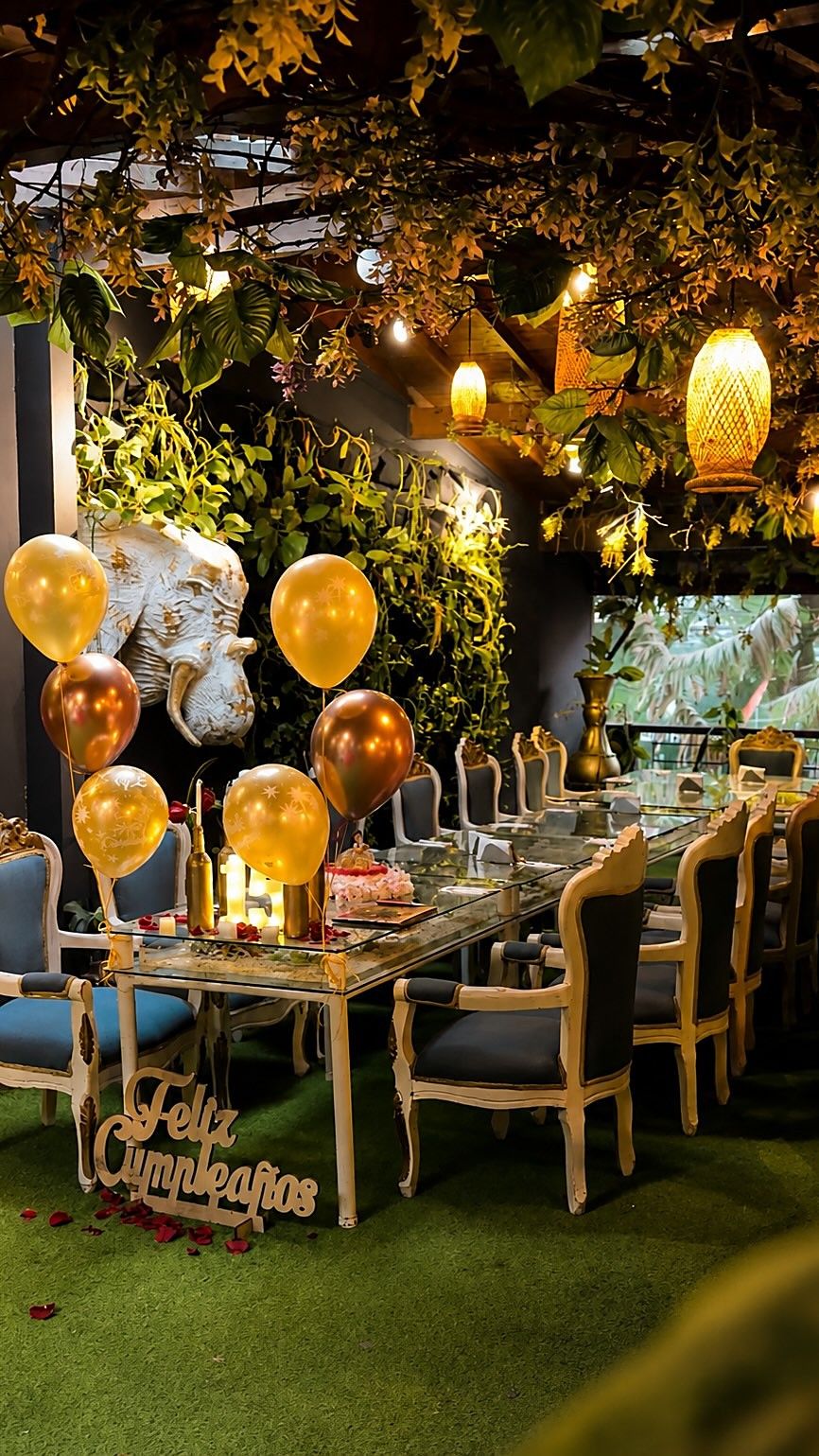 Mesa larga decorada para un cumpleaños en el Bosque Isabelino de Mystic, con globos dorados y velas